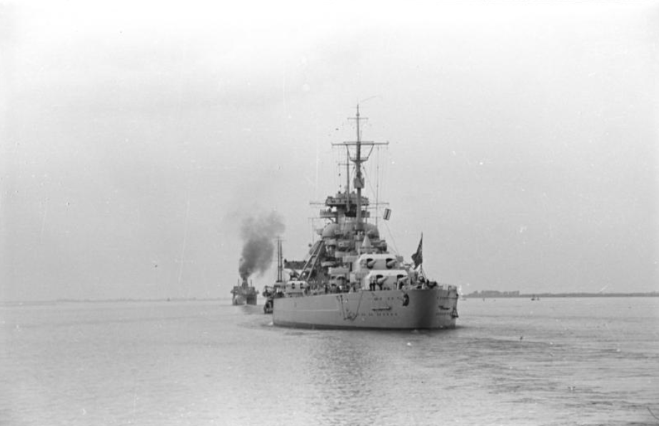 Two warships on water, one large in foreground, one smaller behind, both emitting smoke. Black and white photo.