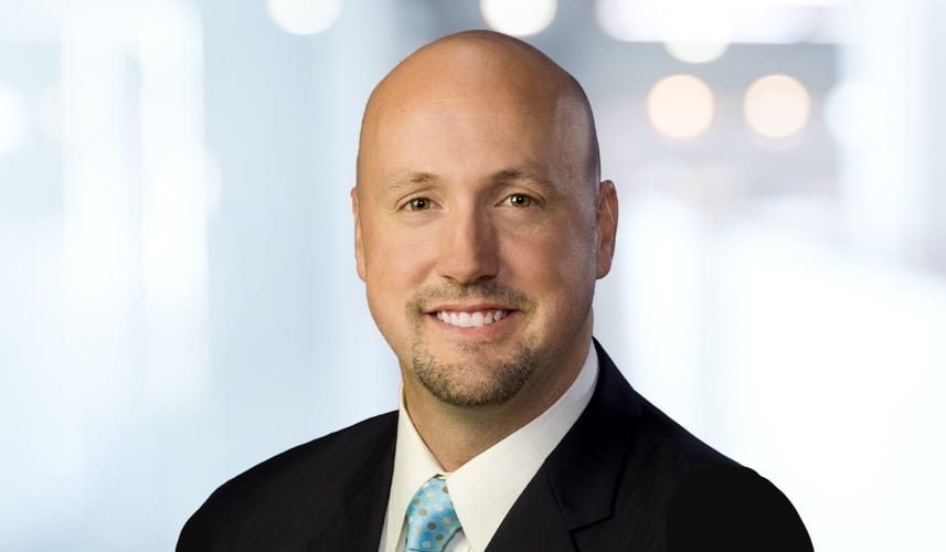 Smiling bald man with a goatee in a suit.