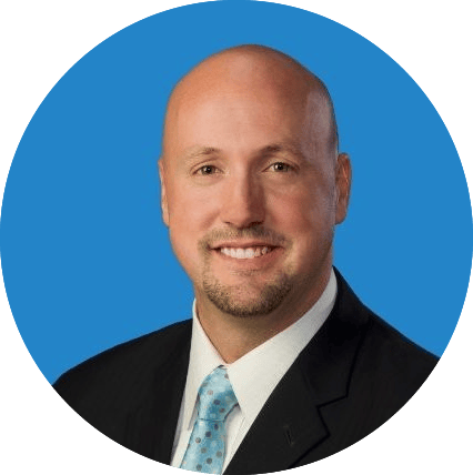 Smiling bald man with beard in suit and tie on a blue background.