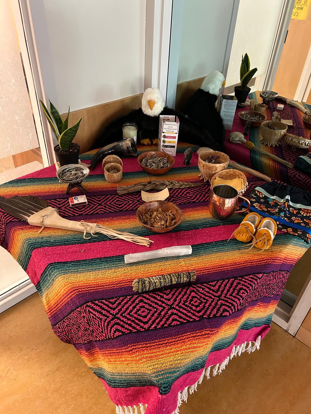 Table display with indigenous medicines, a pair of moccasins and other artefacts.  