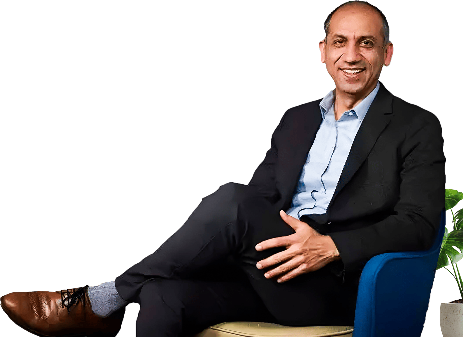 A smiling man in a suit sits relaxed in a chair.