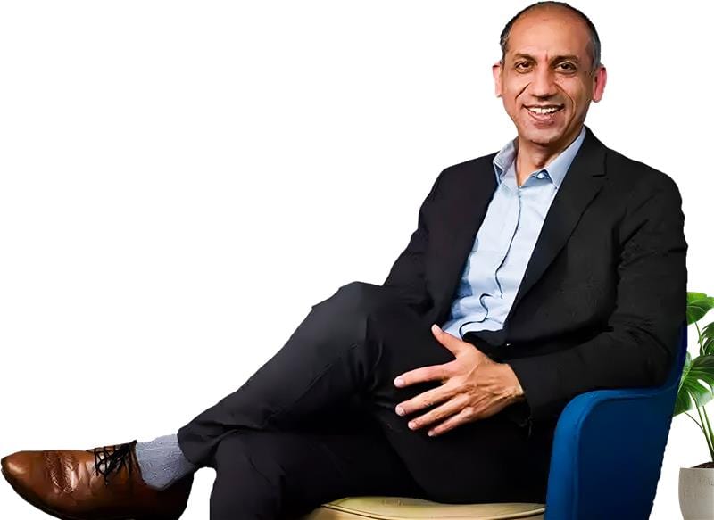 Smiling man in black suit, seated.