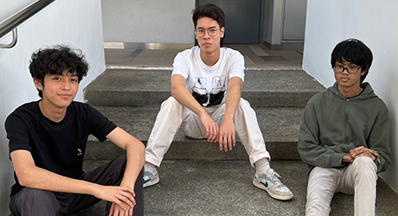 Three young men in casual attire sit on concrete steps.