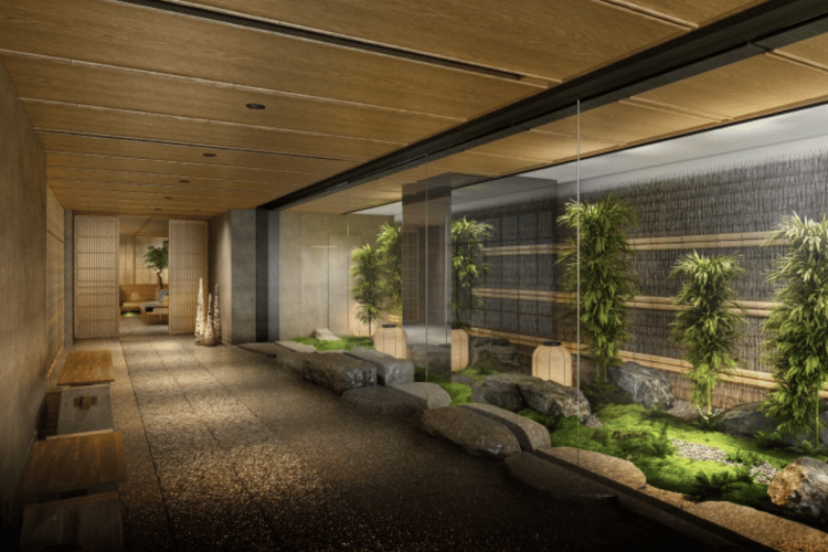 An indoor hallway with a wooden ceiling, leading to sliding doors, alongside a serene rock garden with bamboo.