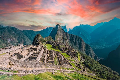 Machu Picchu, the ancient Inca city nestled in the Andes mountains, under a vibrant sunset sky.