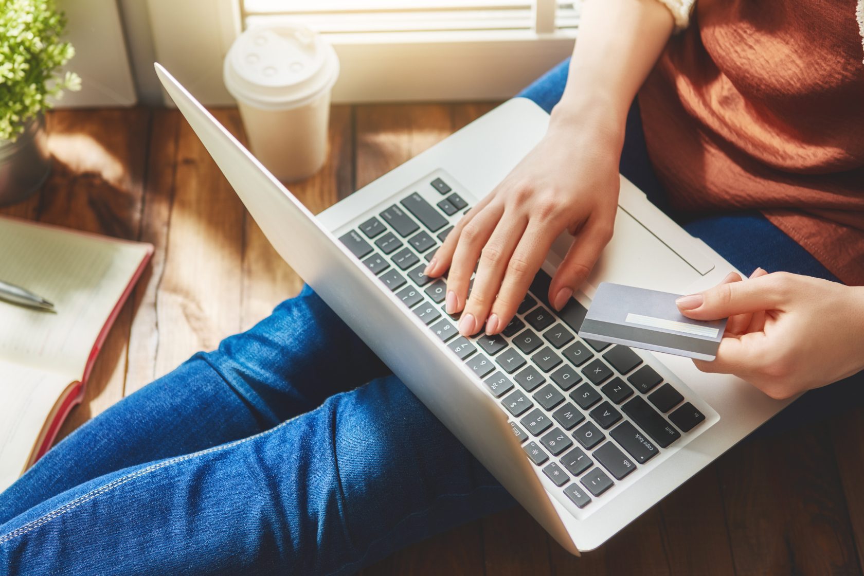 Person on laptop holding a credit card, ready for online shopping.