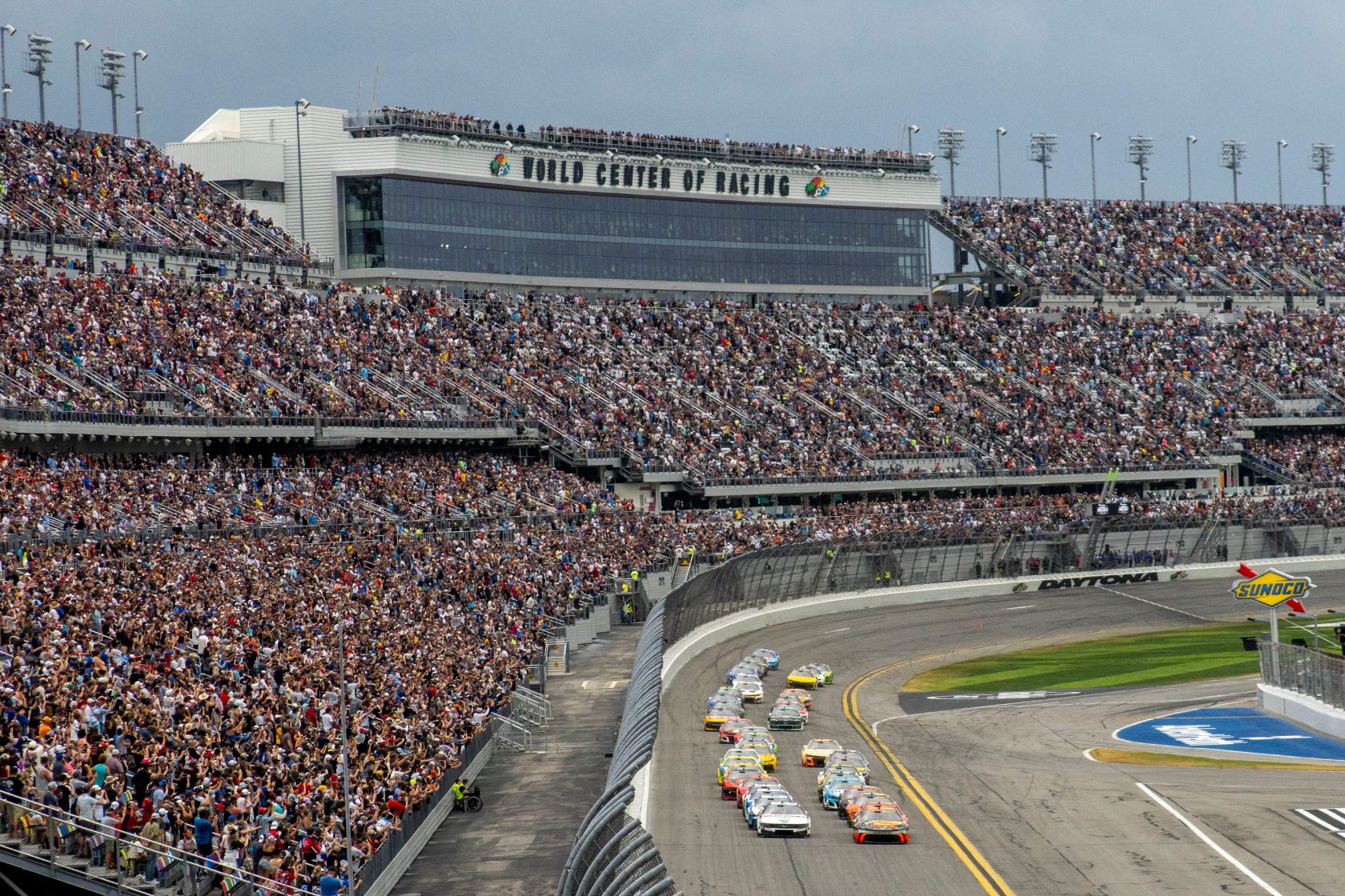 Packed race track stadium with cars racing.
