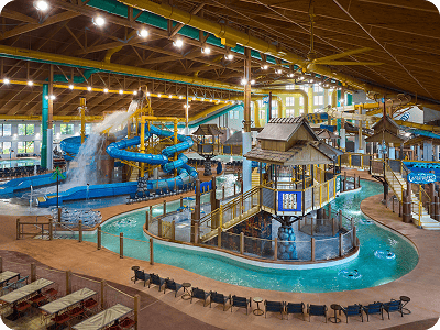 Indoor water park with blue slides, a lazy river, and multi-level play areas under a high ceiling.