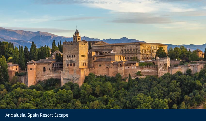 The Alhambra palace in Andalusia, Spain, surrounded by lush trees and distant mountains.