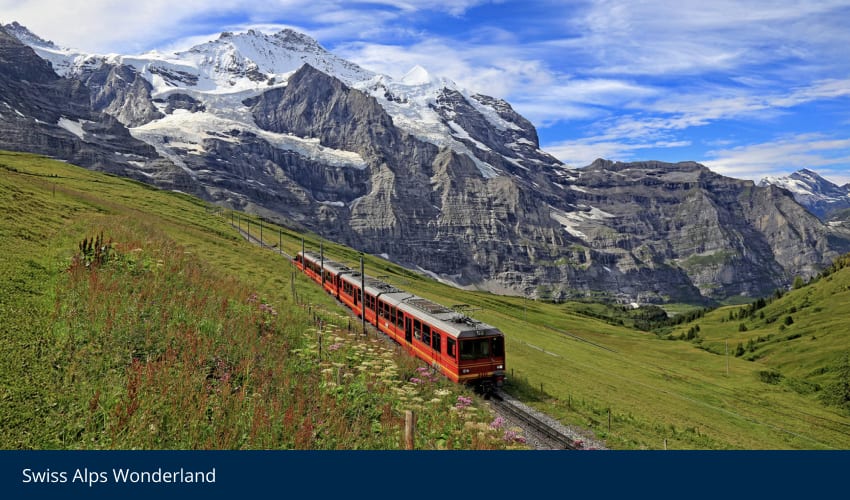 Red train on a mountain track with snow-capped Swiss Alps under a blue sky.