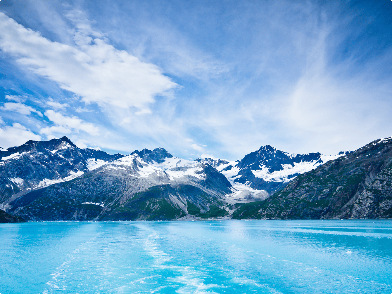 Vibrant turquoise water, snow-capped mountains, and glaciers under a blue sky with clouds.