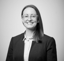 Smiling woman with glasses in a professional black and white headshot.