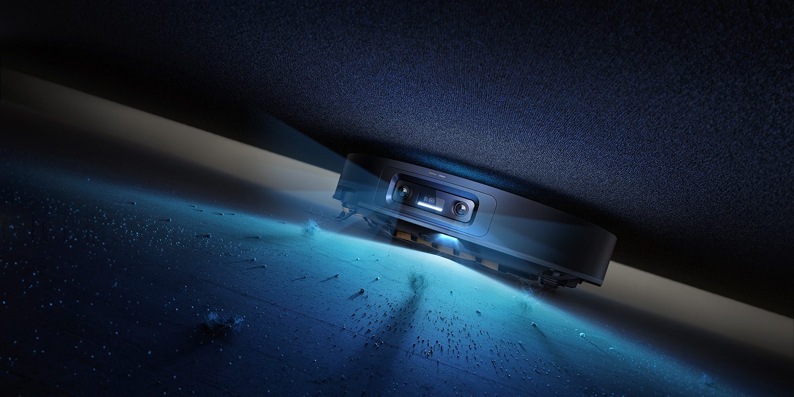 A robot vacuum illuminates and cleans dust from under dark furniture, highlighted by its bright light.