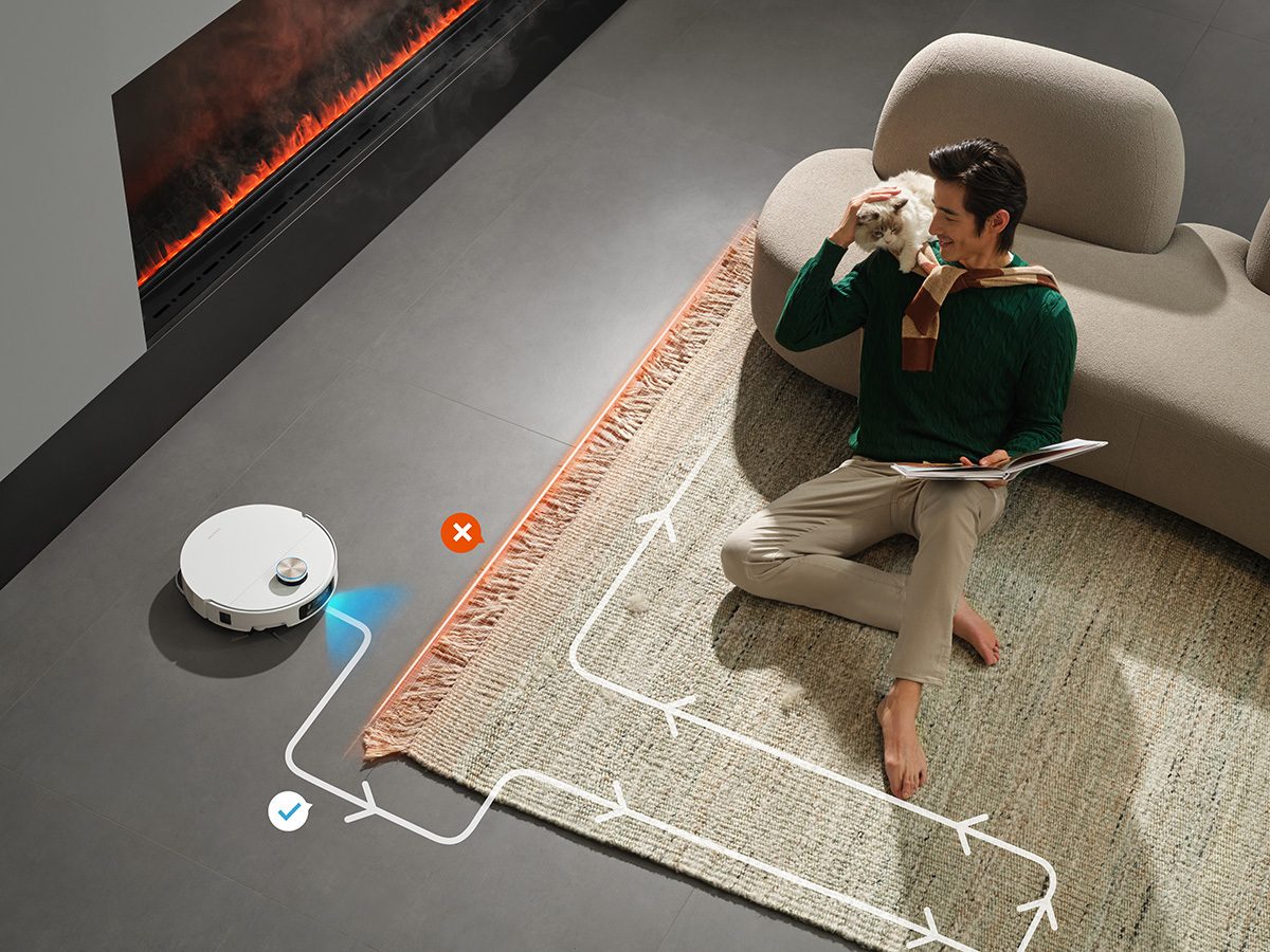 A robot vacuum cleans around a man petting a cat on a rug, with a smart cleaning path shown.