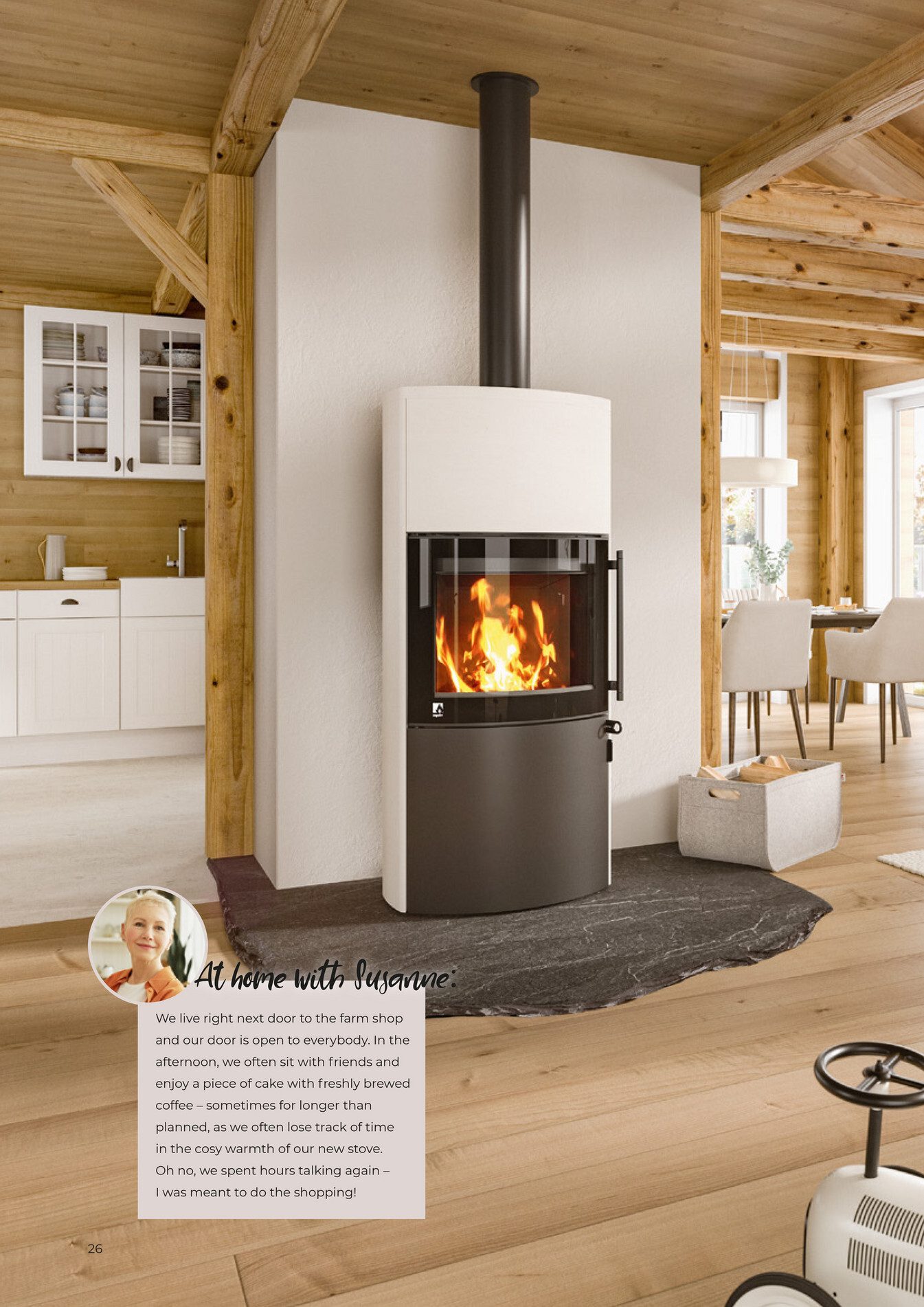 Modern wood-burning stove in a rustic, open-plan home with timber beams, kitchen, and dining area.