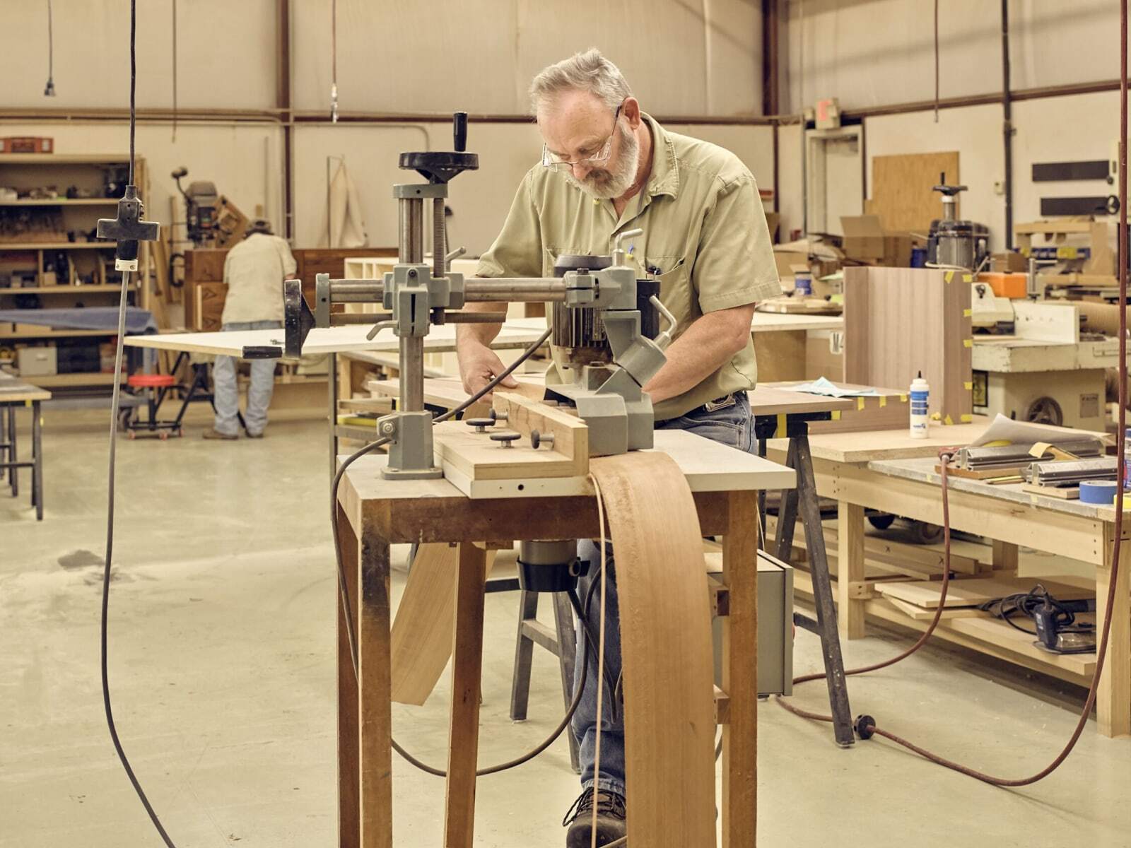 Man uses a woodworking machine on wood in a workshop.