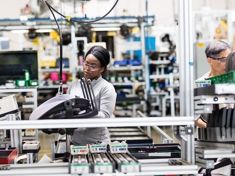 Two workers assemble products in a manufacturing facility.