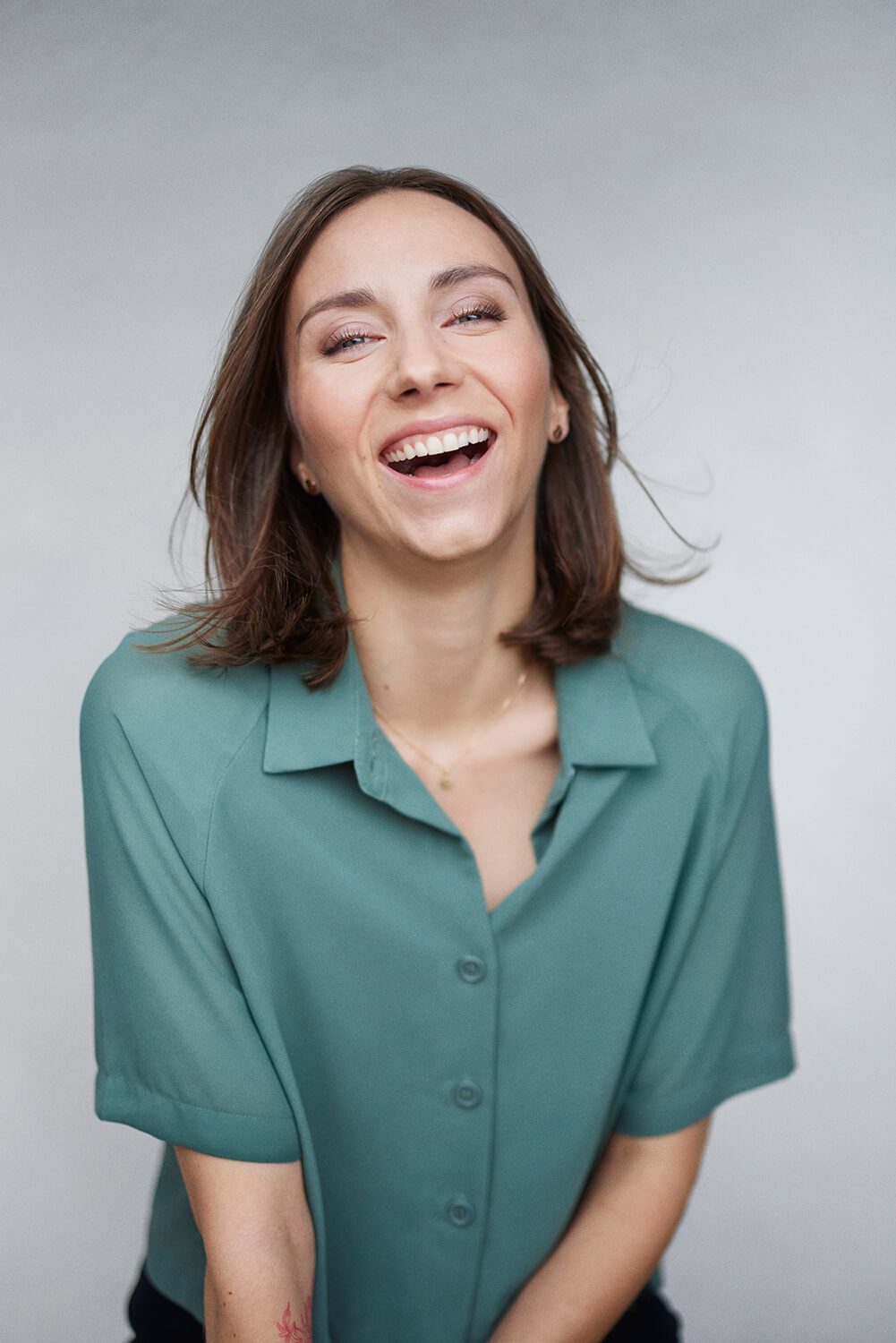 Woman in a green shirt, laughing heartily.