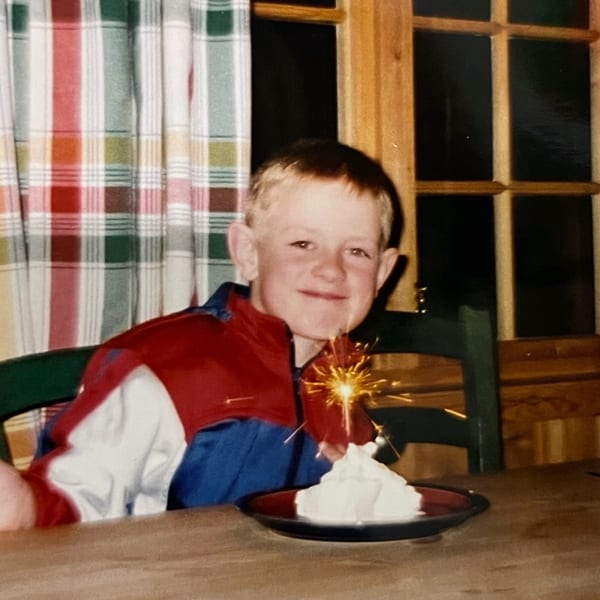 Smiling boy with cake and sparkler.