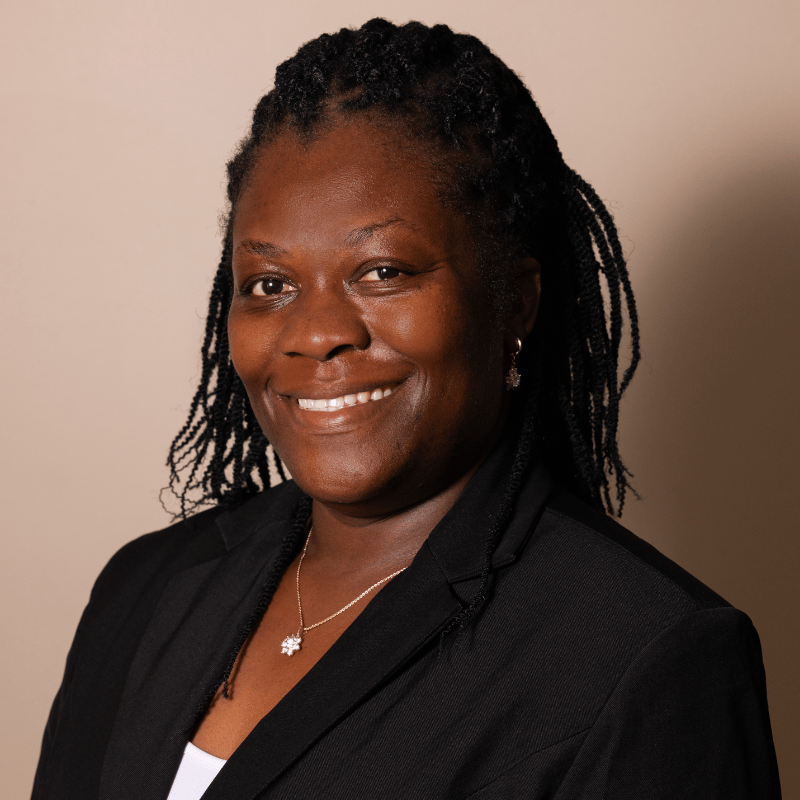 A smiling woman with braided hair and a black blazer looking directly at the camera.