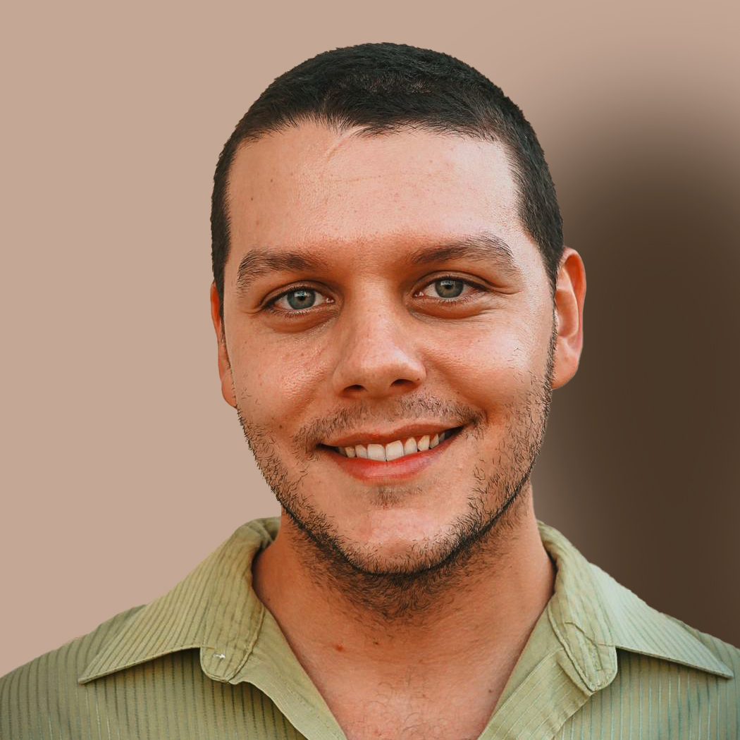 A man with short dark hair and light eyes smiles warmly at the camera.