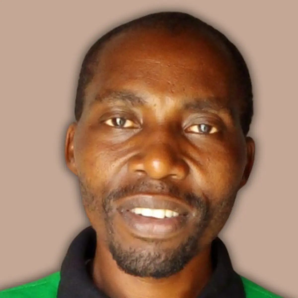 Headshot of a man with dark skin and a beard, wearing a green and black polo shirt, looking at the camera.