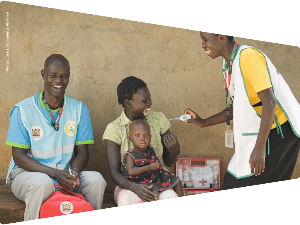 Health workers check a child's temperature, observed by the mother, in a community health program.