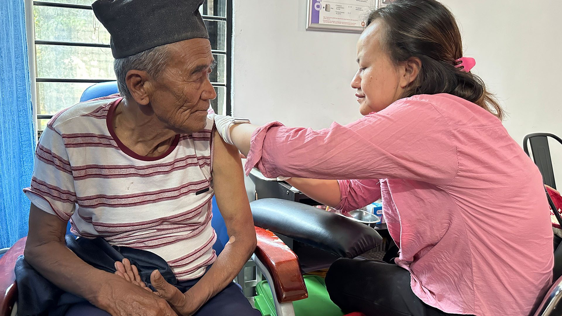 Elderly man receives an injection in his arm from a woman.