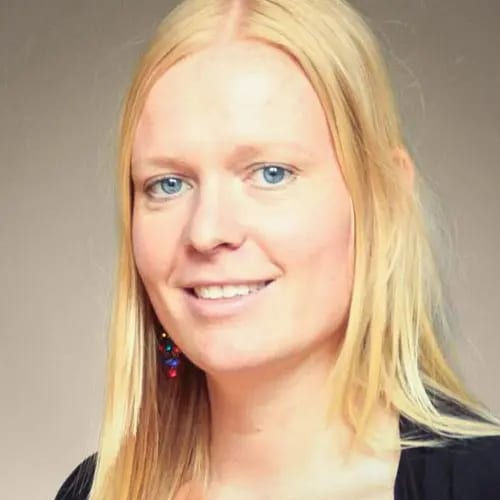 A smiling woman with blonde hair and blue eyes, wearing a colorful earring.