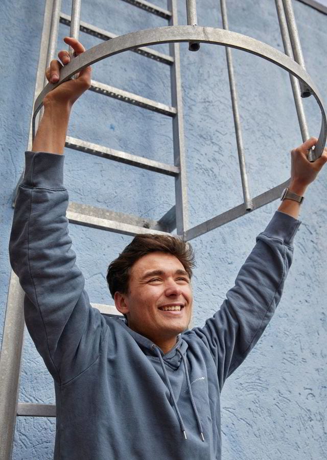 Flash photography, Clothing, Smile, Outerwear, Human, Sleeve, Standing, Gesture, Happy, Wall