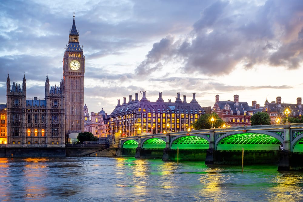 Westminster: Big Ben, Parliament, Westminster Bridge with green lights over Thames at dusk.