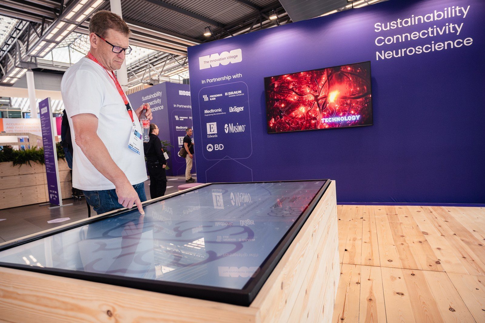 Man uses large interactive display at an event booth themed "Sustainability Connectivity Neuroscience."