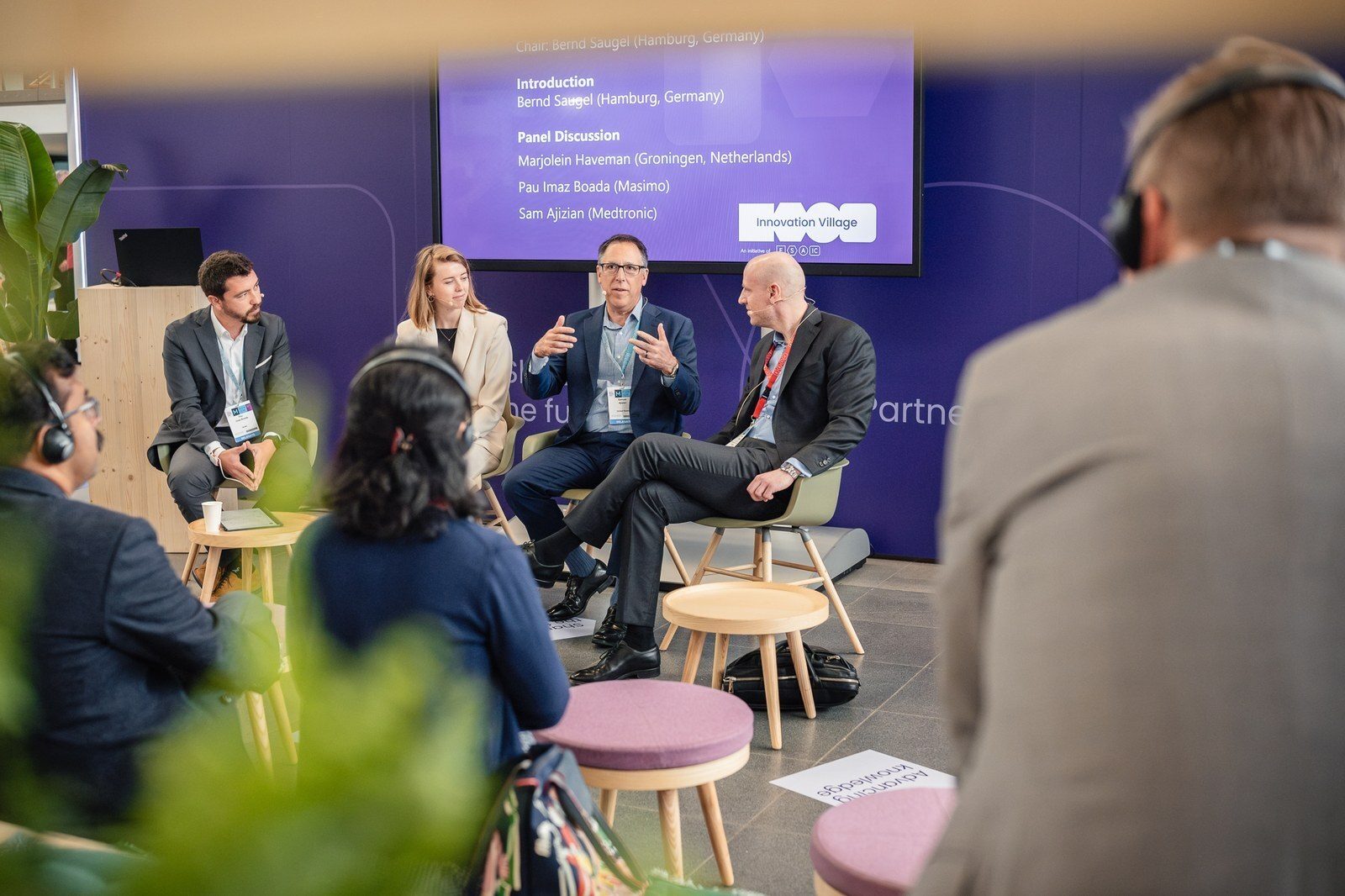 Indoor panel discussion with four speakers and an audience.