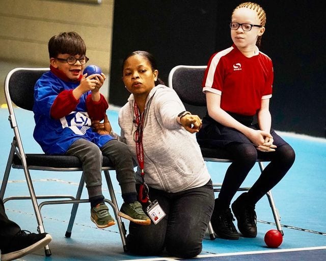 boy holds boccia ball with big smile