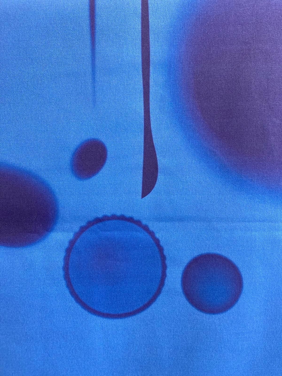 Abstract pattern of dark circles and lines on blue fabric.