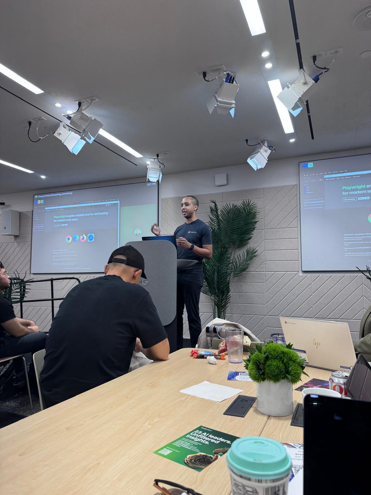 A man presents "Playwright" testing software to an audience in a modern meeting room.