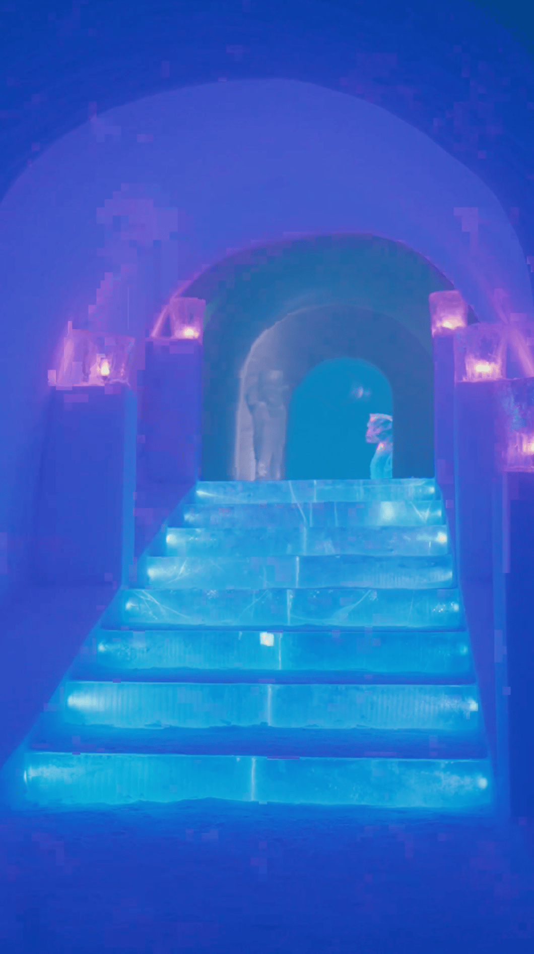 Ice tunnel with blue illuminated steps, purple accents, and a person at the end.