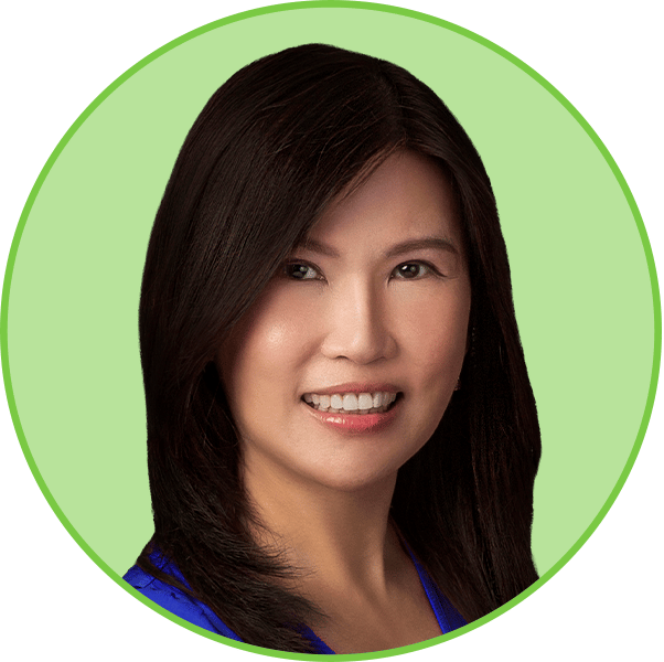 Headshot of a smiling Asian woman with long dark hair against a light green background.
