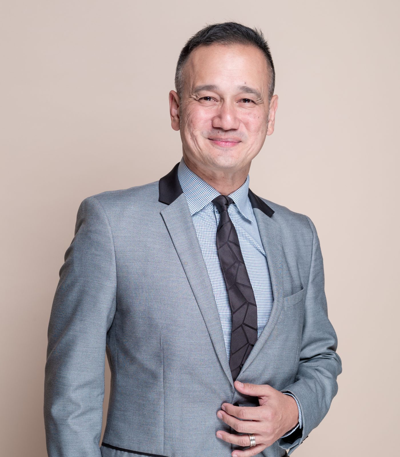 Man in a gray suit and tie, smiling.