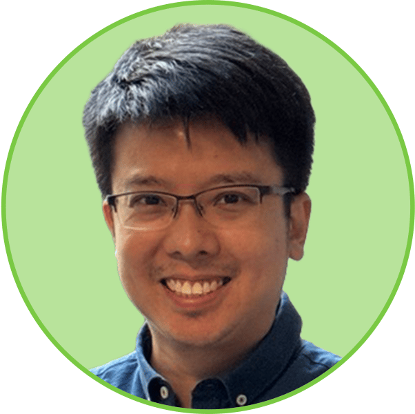 A smiling man with dark hair and glasses wearing a blue collared shirt.