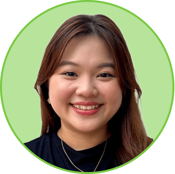 A young woman with long brown hair smiles brightly, wearing a black shirt and a necklace.