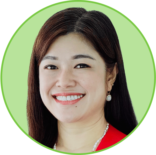 Smiling Asian woman with dark hair, red top, and pearl necklace, on a green background.