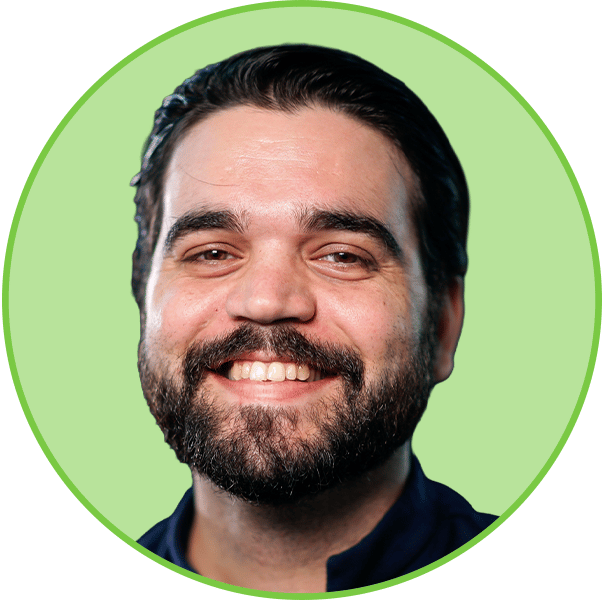 Close-up headshot of a smiling man with a beard, set against a vibrant green circular background.
