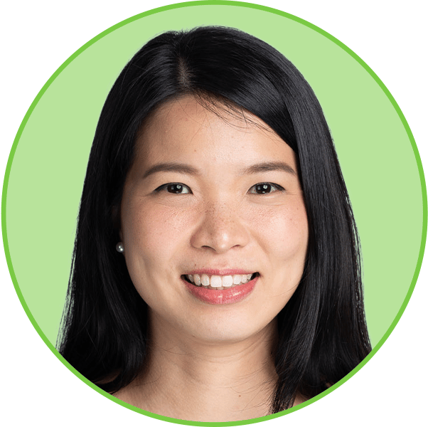 Headshot of a smiling Asian woman with long dark hair, wearing pearl earrings, looking at the camera.