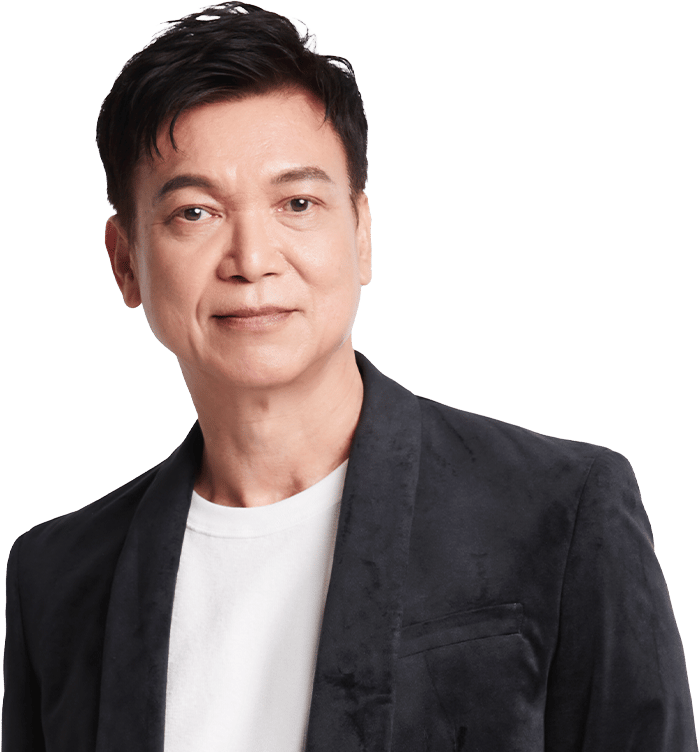 A man in a dark blazer and white t-shirt smiles against a dark green background.
