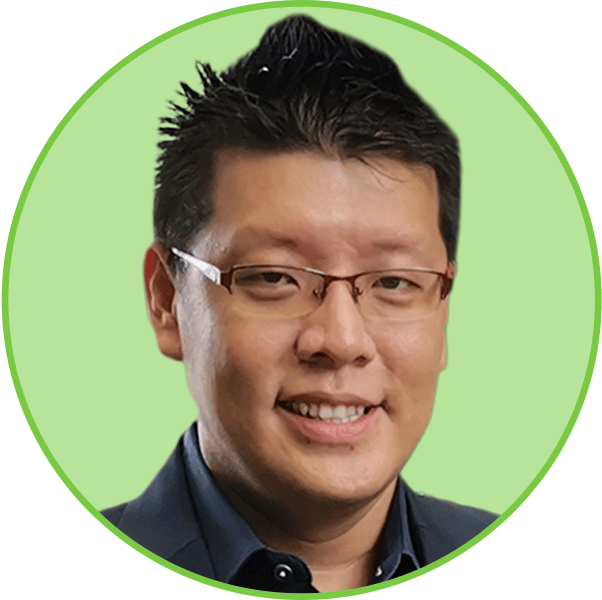 Headshot of a smiling Asian man with glasses and spiky hair, wearing a dark suit against a green circular background.