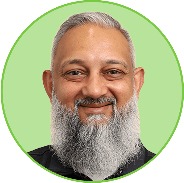 Close-up of a smiling man with a grey beard and grey hair, looking directly at the viewer.