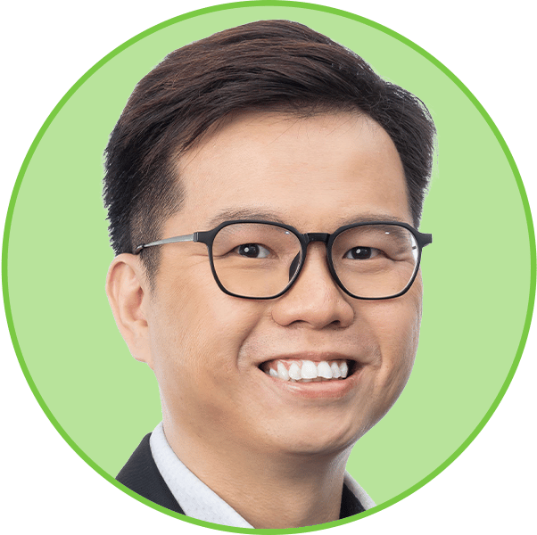 A smiling Asian man with short dark hair and black-framed glasses, against a light green background.