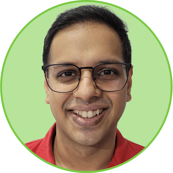Smiling man in glasses and red shirt against a green background.