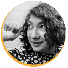 B&W smiling woman with curly hair and nose ring, looking up, fist raised.